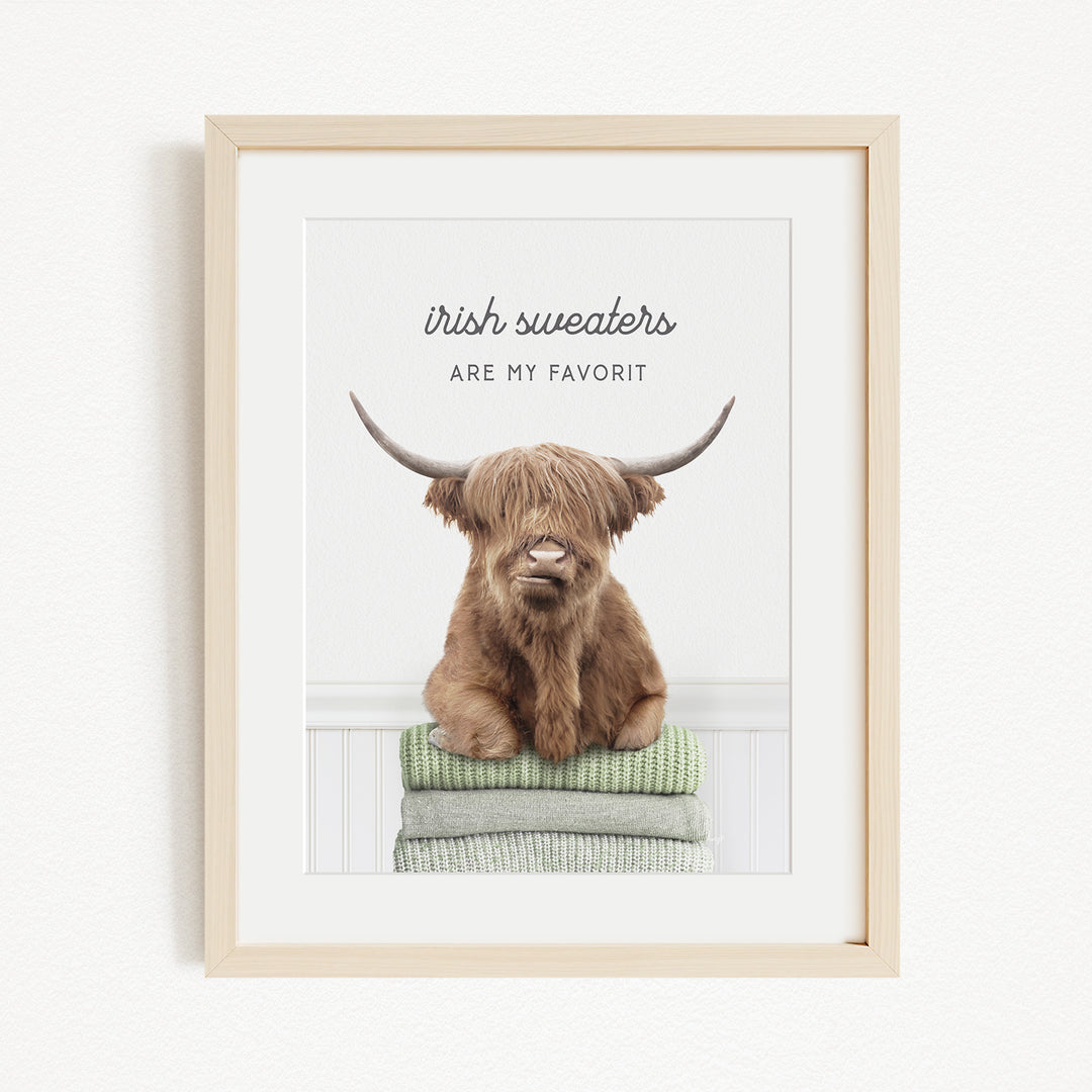 a brown cow with long horns sitting on a stack of green and gray blankets, with the text "Irish sweaters are my favorite" written above the cow.