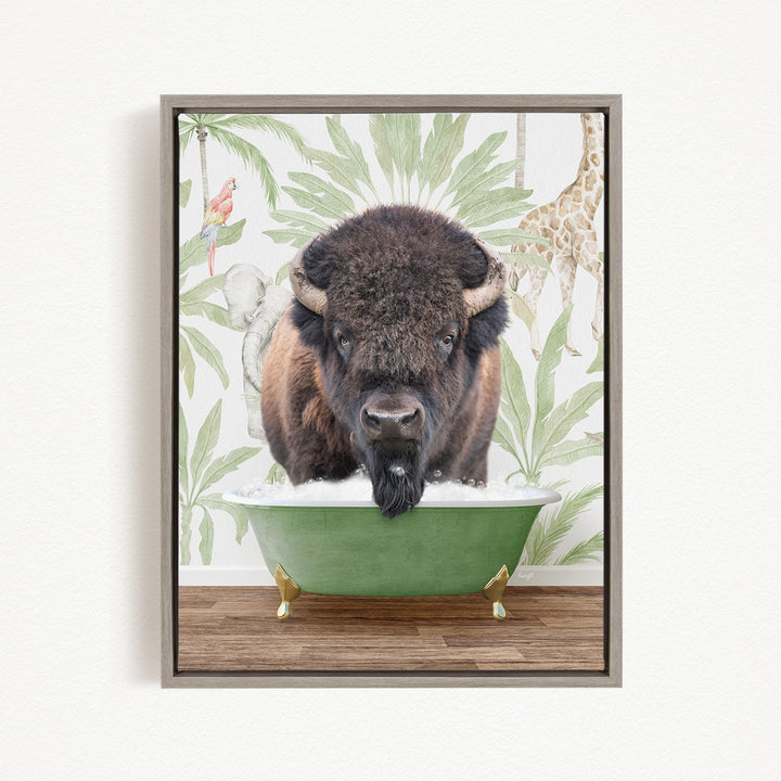 A buffalo is sitting in a green bathtub, surrounded by tropical foliage and a giraffe in the background.