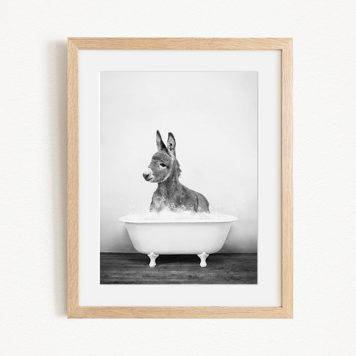 A donkey is sitting in a bathtub filled with water, creating a playful and whimsical scene.
