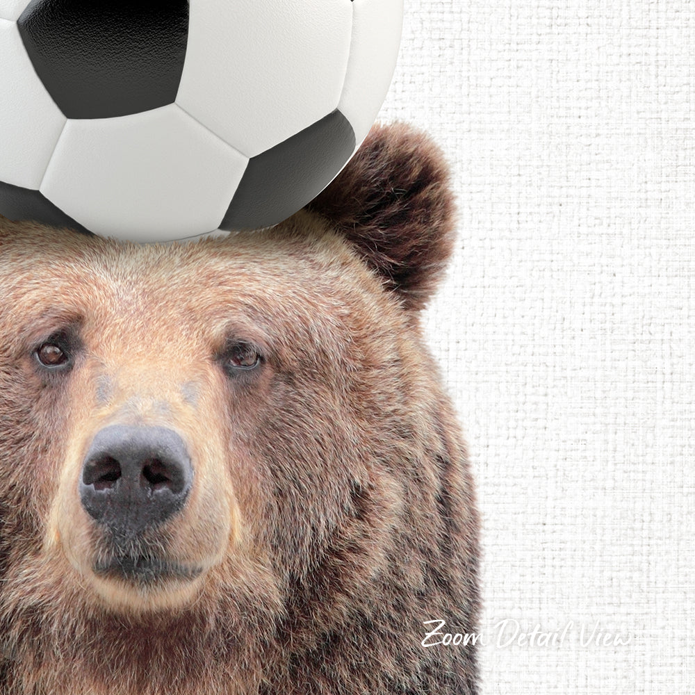 A close-up of a brown bear's face with a soccer ball resting on its head.