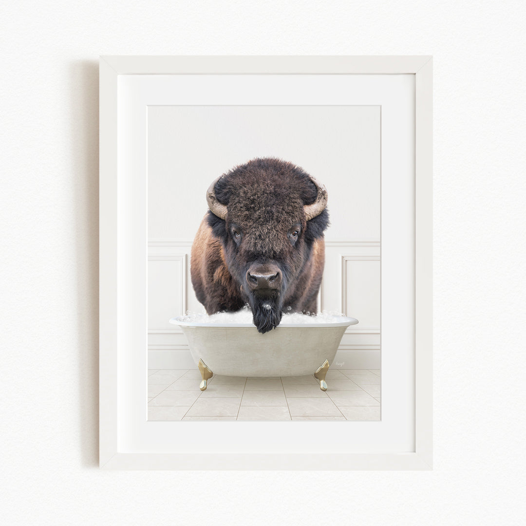 A buffalo with large horns is sitting in a white bathtub filled with water, appearing to be enjoying a bath.