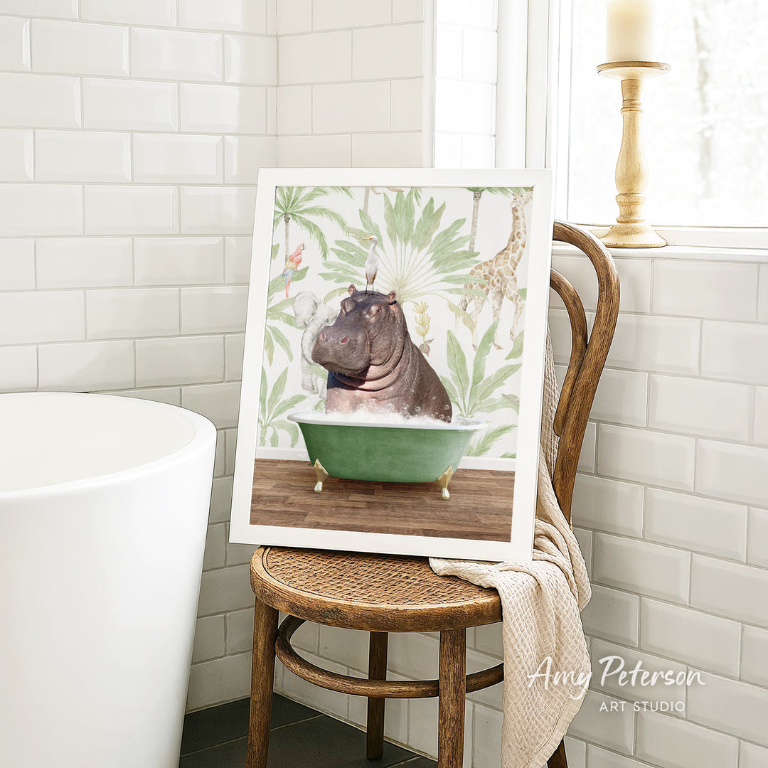 A framed image of a hippopotamus sitting in a green bathtub is displayed on a wooden chair in a bathroom setting.