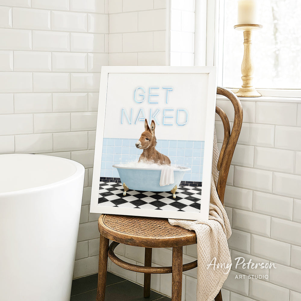 A framed image of a dog sitting in a bathtub, with the text "GET NAKED" displayed on the frame.