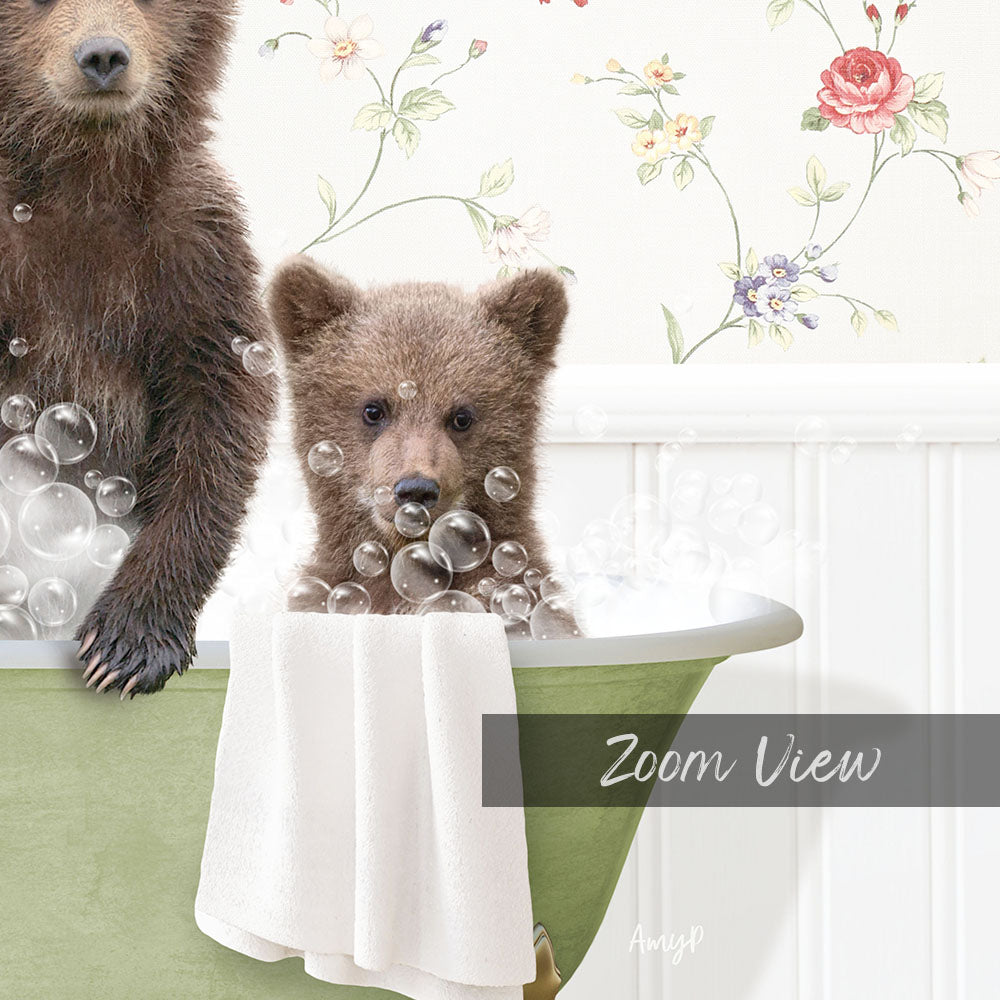 A baby bear sitting in a bathtub filled with bubbles, with a towel draped over the side of the tub.