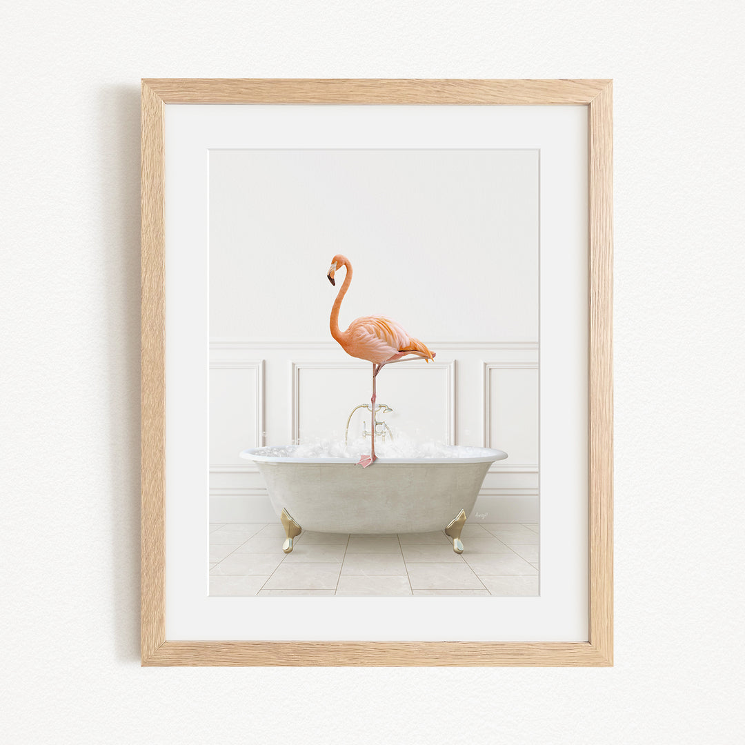 A framed image of a pink flamingo standing on the edge of a white bathtub filled with water.