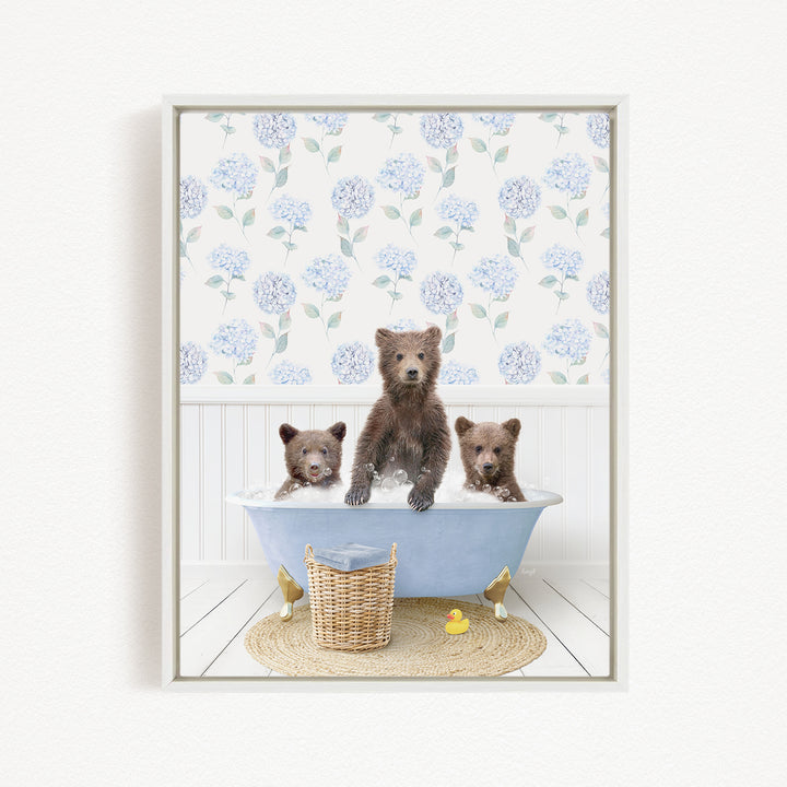 A framed image depicting three adorable brown bears sitting in a blue bathtub, surrounded by a floral patterned wall and a basket of rubber ducks.