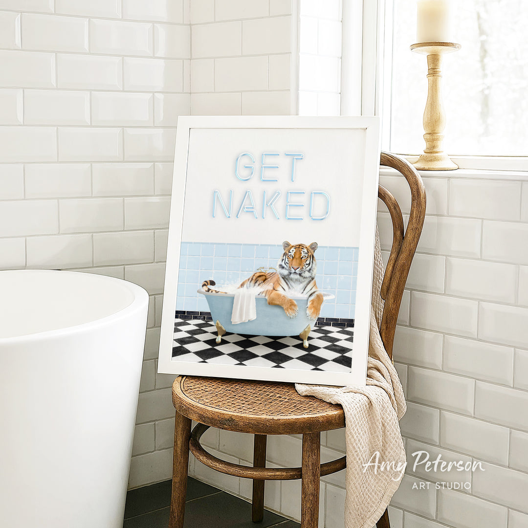 A framed print of a tiger sitting in a bathtub, with the text "GET NAKED" displayed on the frame.