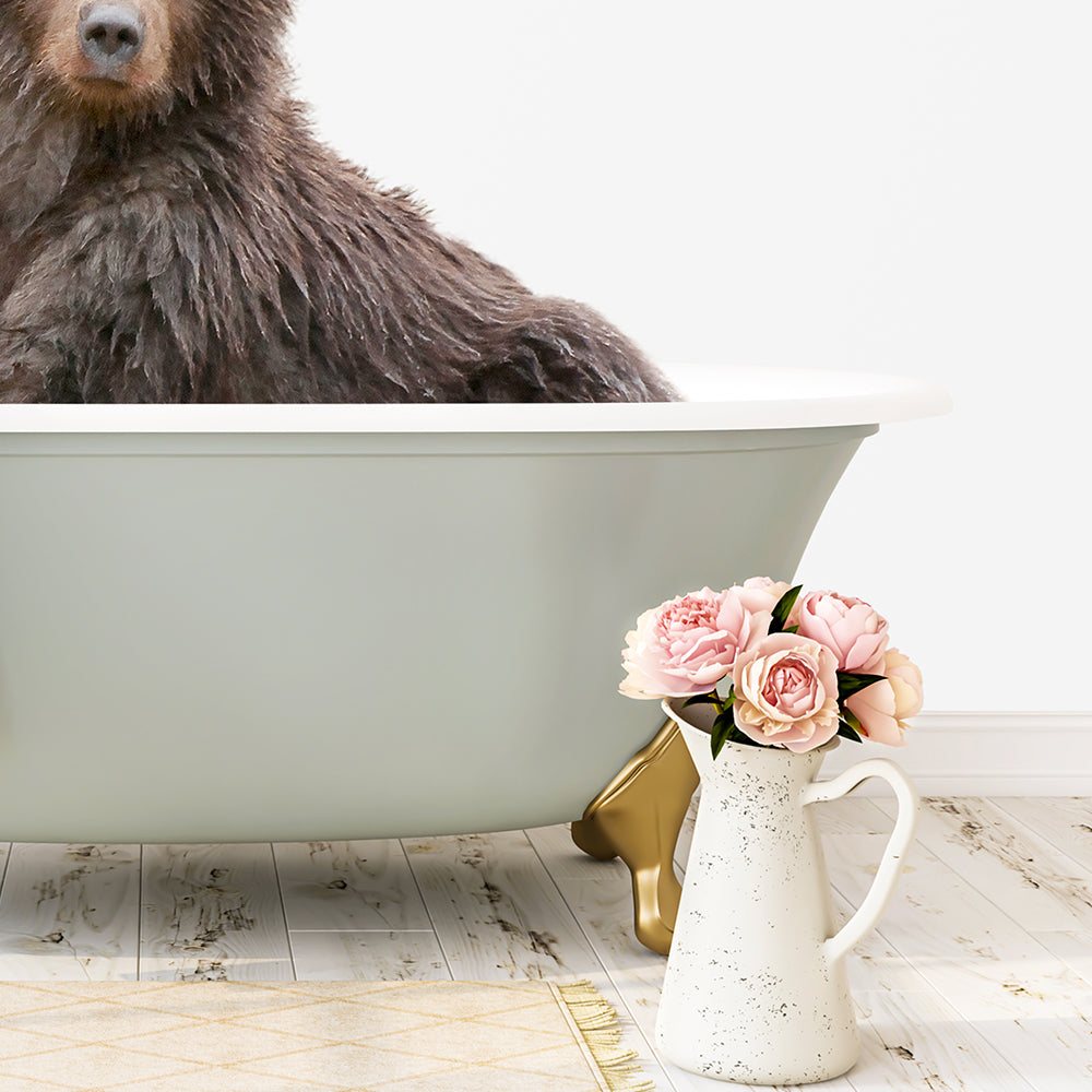 A large brown bear is sitting in a green bathtub, with a vase of pink flowers placed next to it on a white floor.