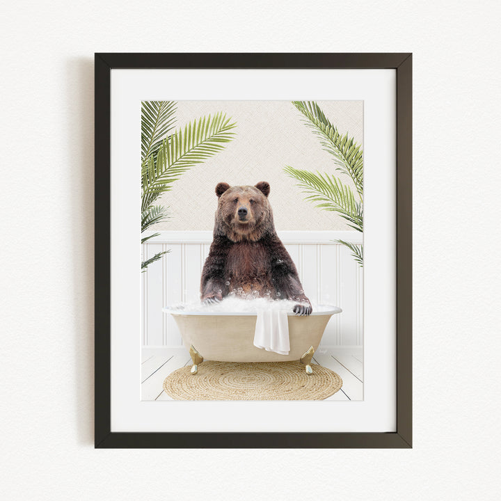 A brown bear sitting in a white bathtub filled with bubbles, surrounded by green palm leaves.