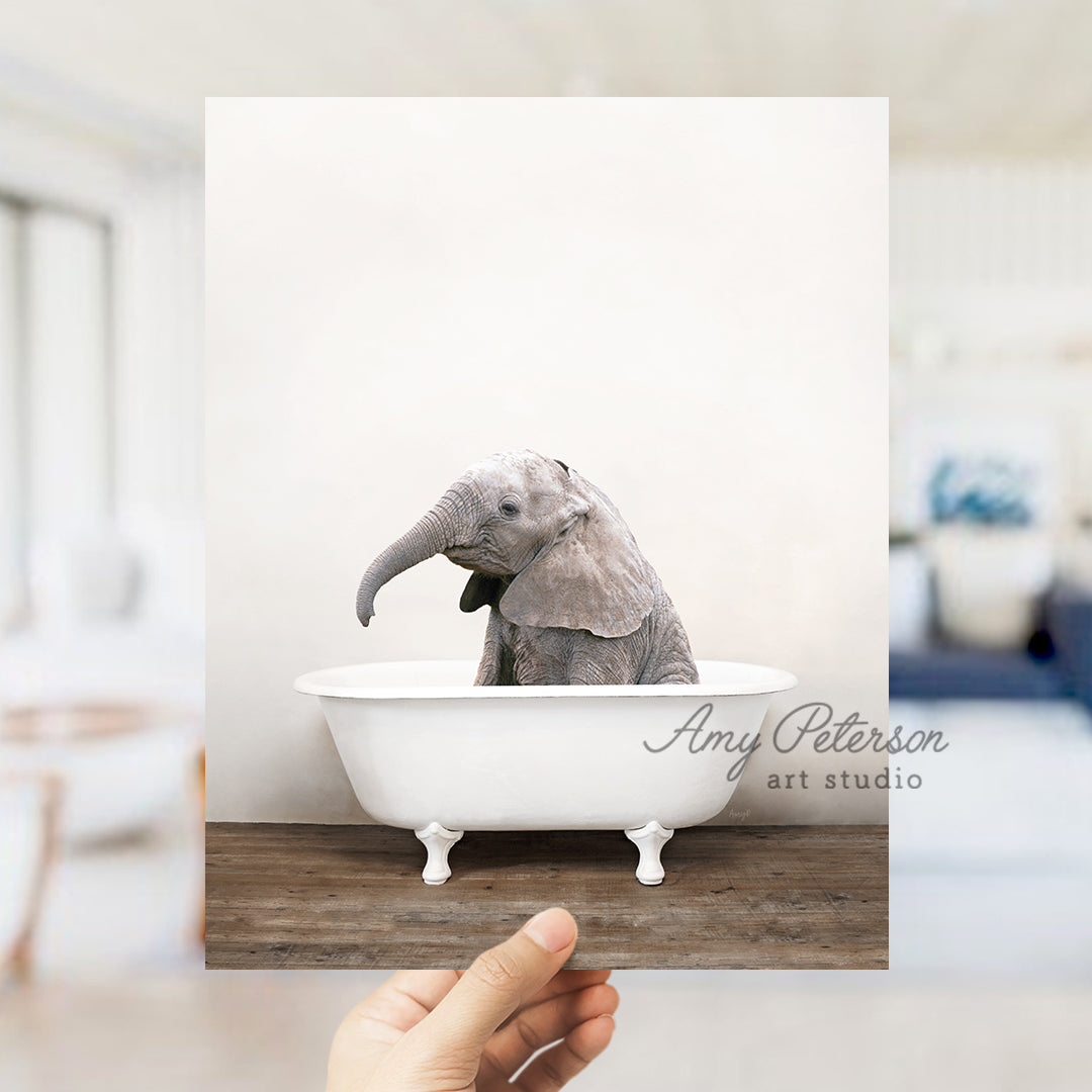 a hand holding up a picture of an elephant in a bathtub