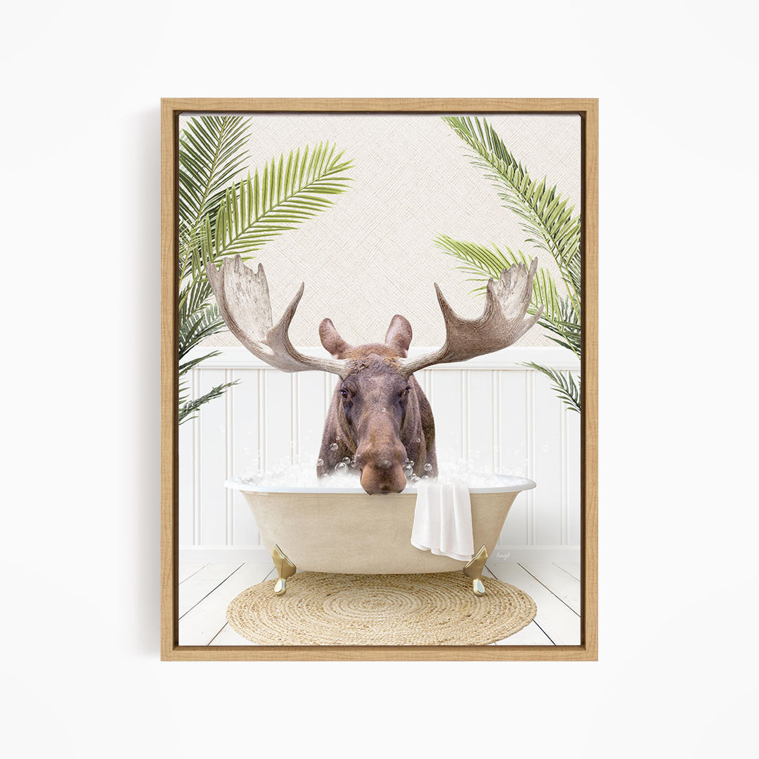 A moose with large antlers is sitting in a bathtub filled with water, surrounded by palm leaves and a woven rug.