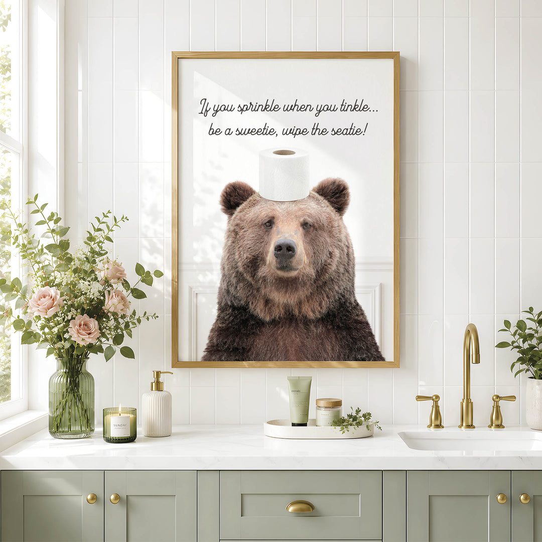 a framed picture of a bear with a toilet paper roll placed on its head, accompanied by a humorous caption.