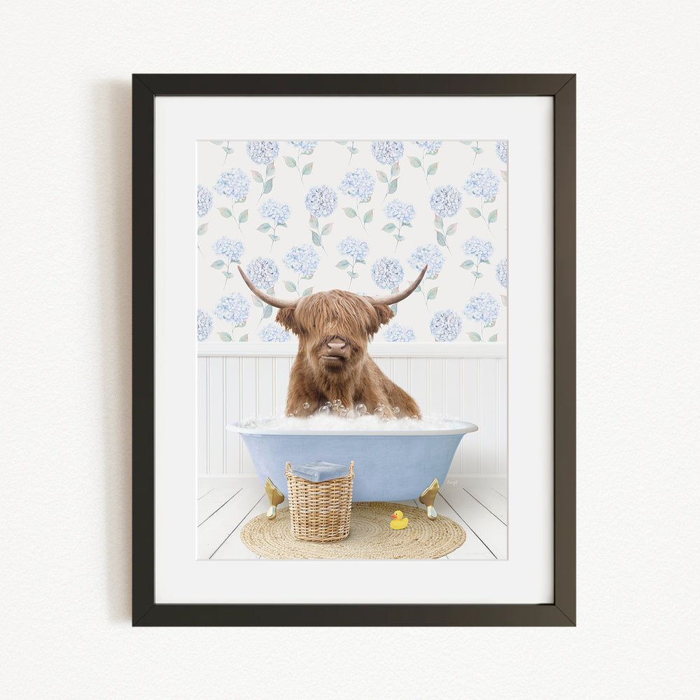A brown cow with long horns is sitting in a blue bathtub filled with bubbles, surrounded by a floral patterned wall and a basket of rubber ducks.