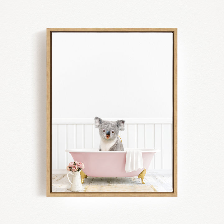 A koala bear sitting in a pink bathtub, surrounded by flowers and a white vase.