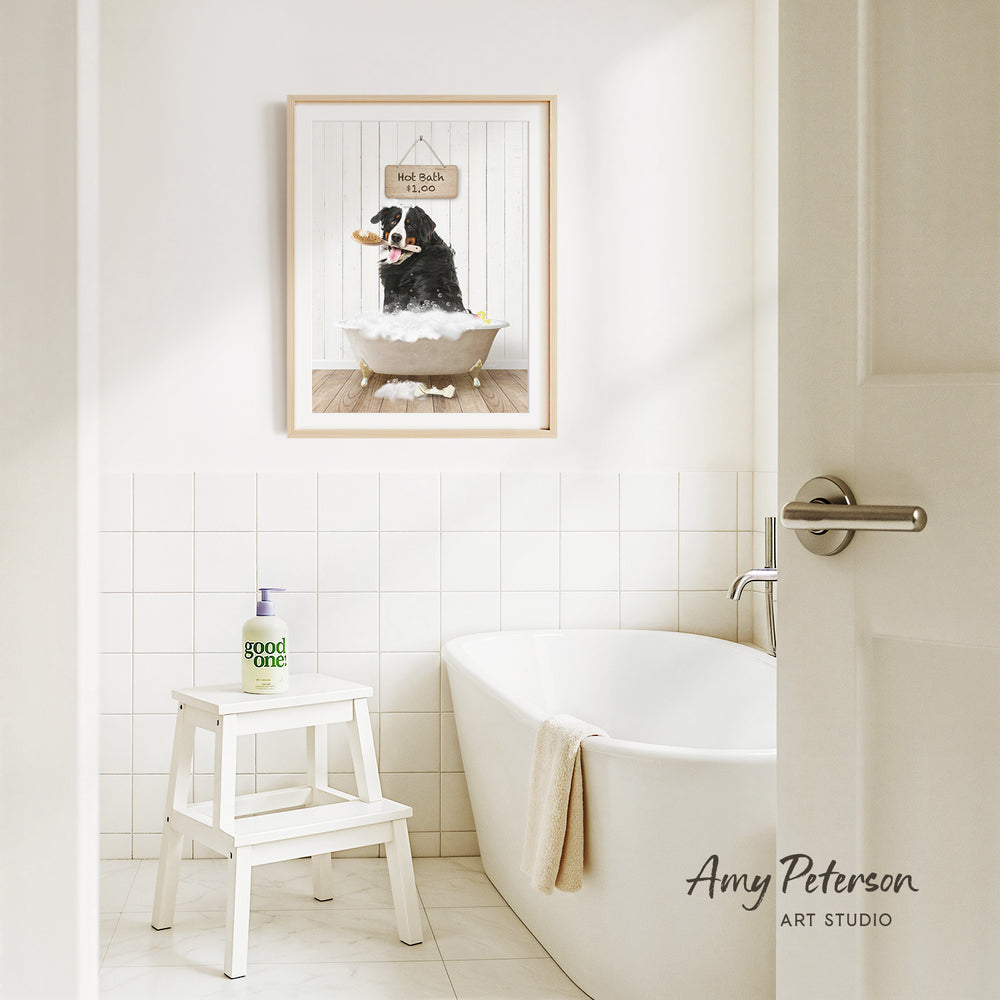 A framed picture of a dog sitting in a bathtub, with a sign above it that says "Hot Bath $1.00", is hanging on the wall above a white bathtub in a bathroom.