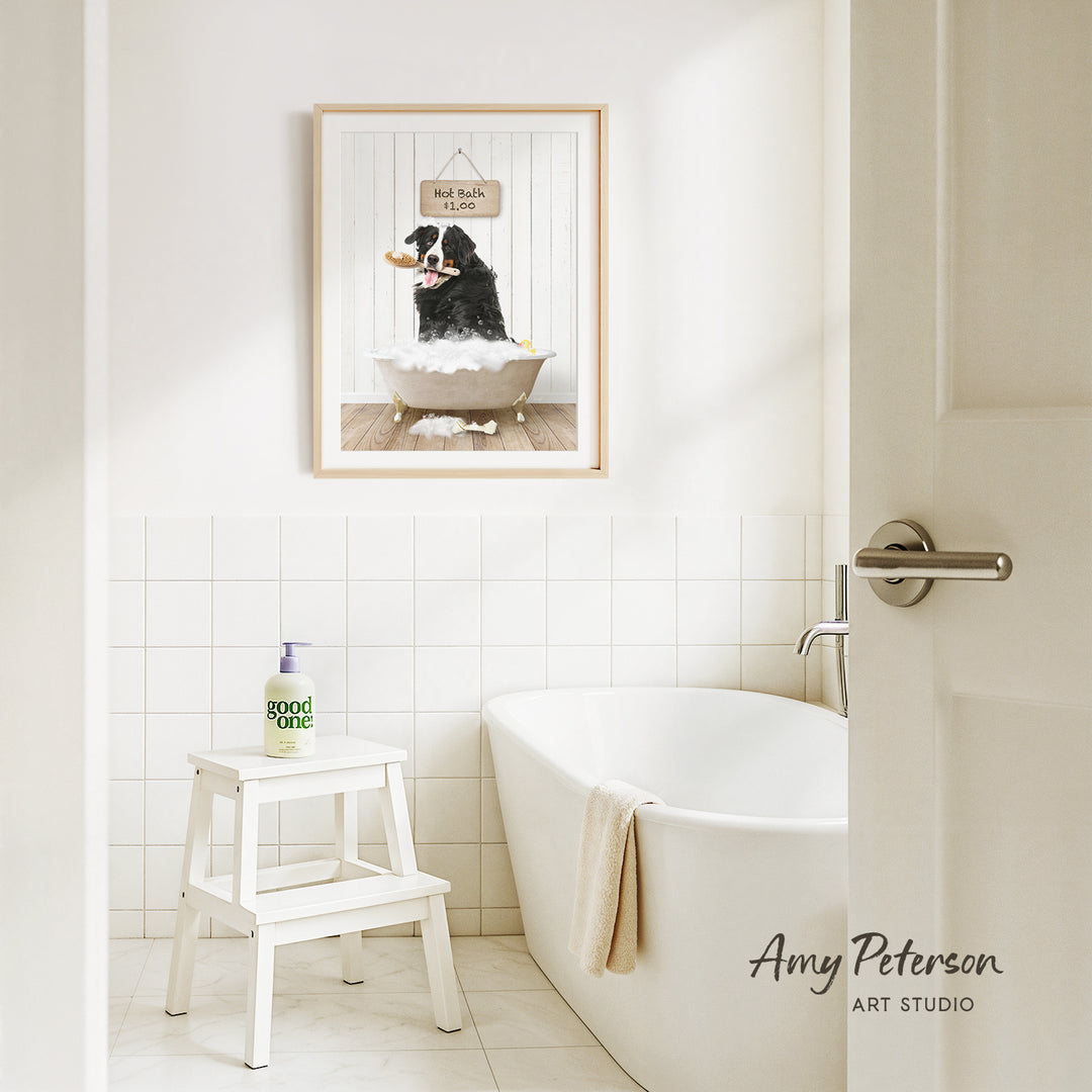 A framed picture of a dog sitting in a bathtub, with a sign above it that says "Hot Bath $1.00", is hanging on the wall above a white bathtub in a bathroom.