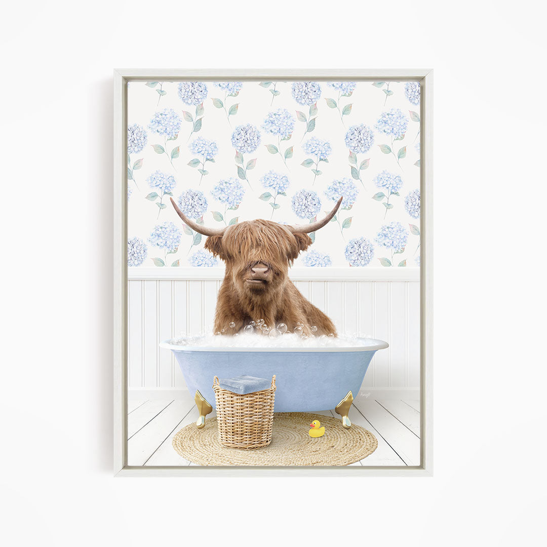 A brown cow with long horns is sitting in a blue bathtub filled with water, surrounded by a wicker basket and a yellow rubber duck.