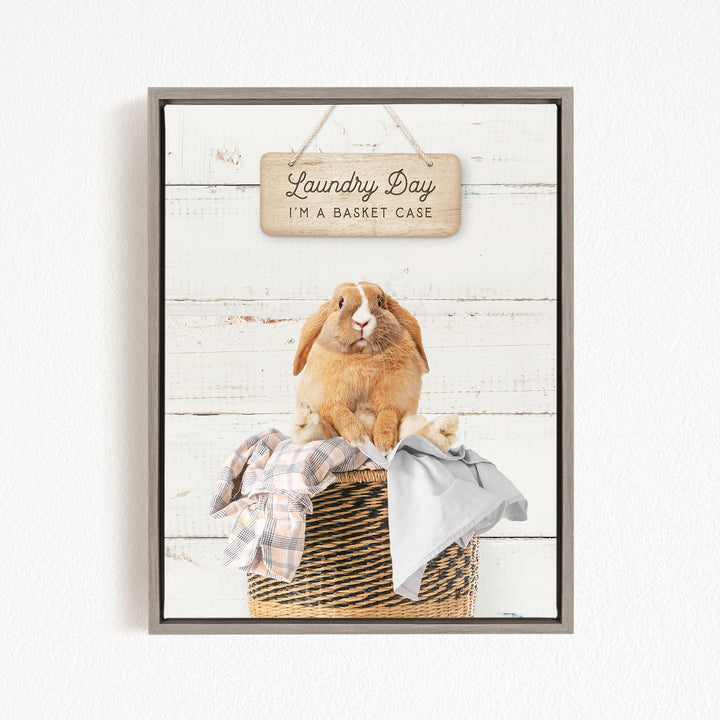 A wooden sign with the text "Laundry Day I'm a basket case" hangs above a woven basket containing clothes and a small rabbit.