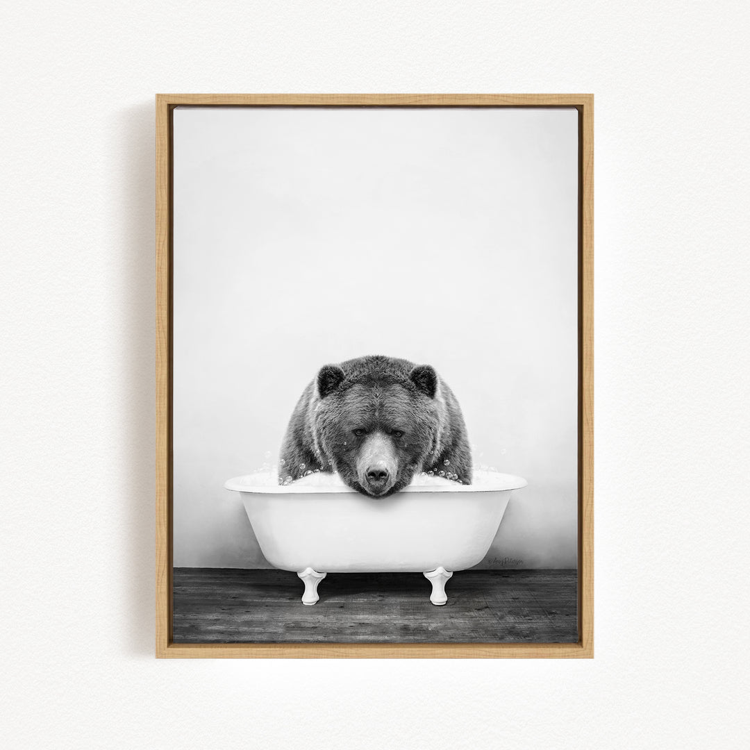 A black and white photograph of a bear sitting in a bathtub filled with water.
