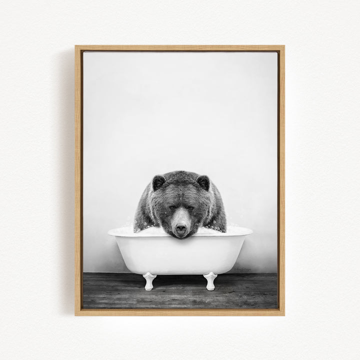 A black and white photograph of a bear sitting in a bathtub filled with water.