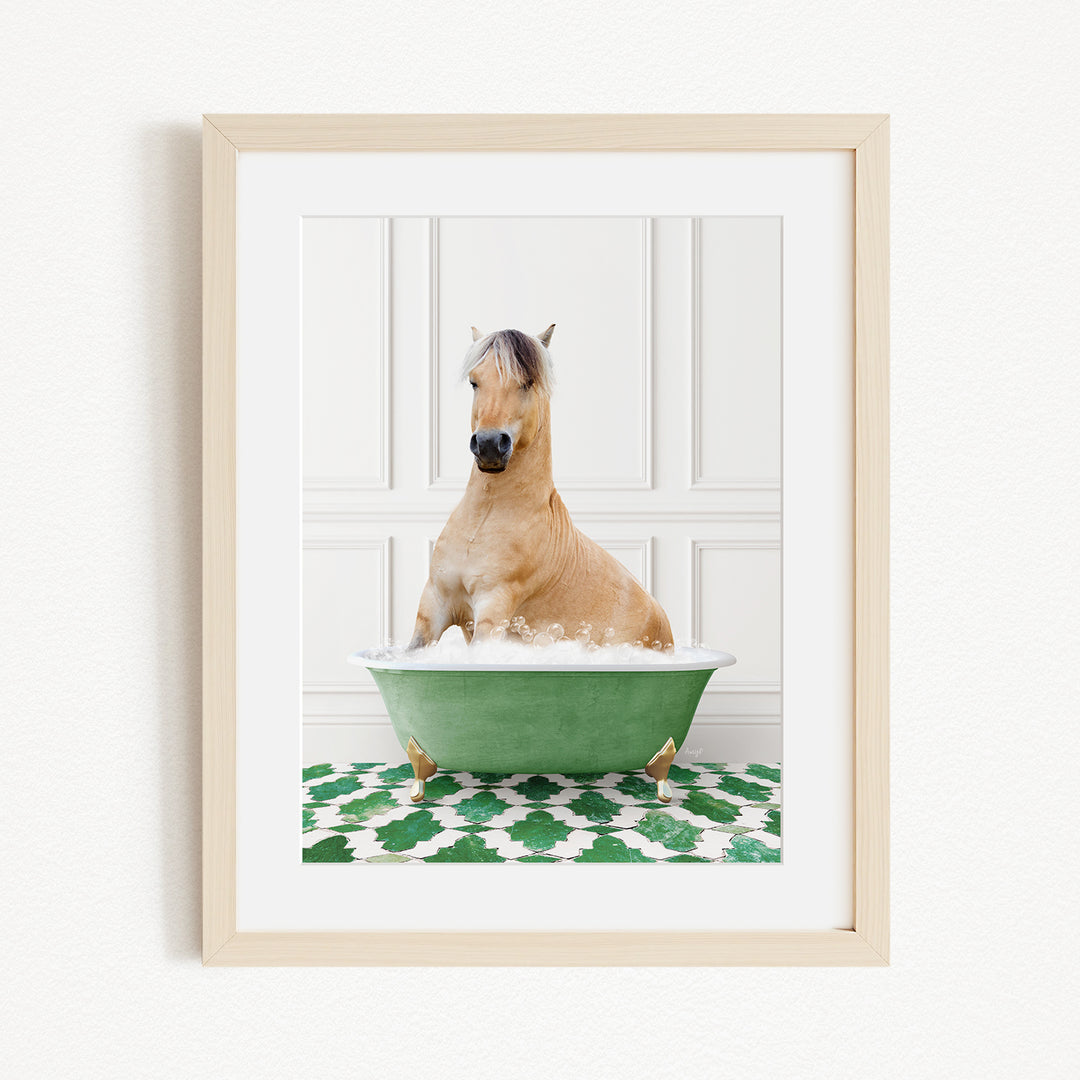 A light brown horse is sitting in a green bathtub filled with water, surrounded by a green and white patterned rug.