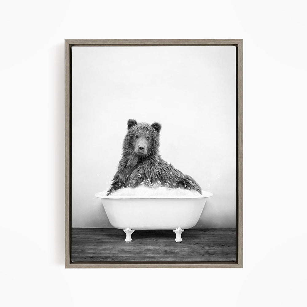 A black and white image of a bear sitting in a bathtub filled with water.