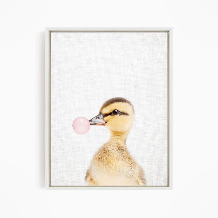 A cute duckling blowing a bubble with a pink bubble gum bubble.