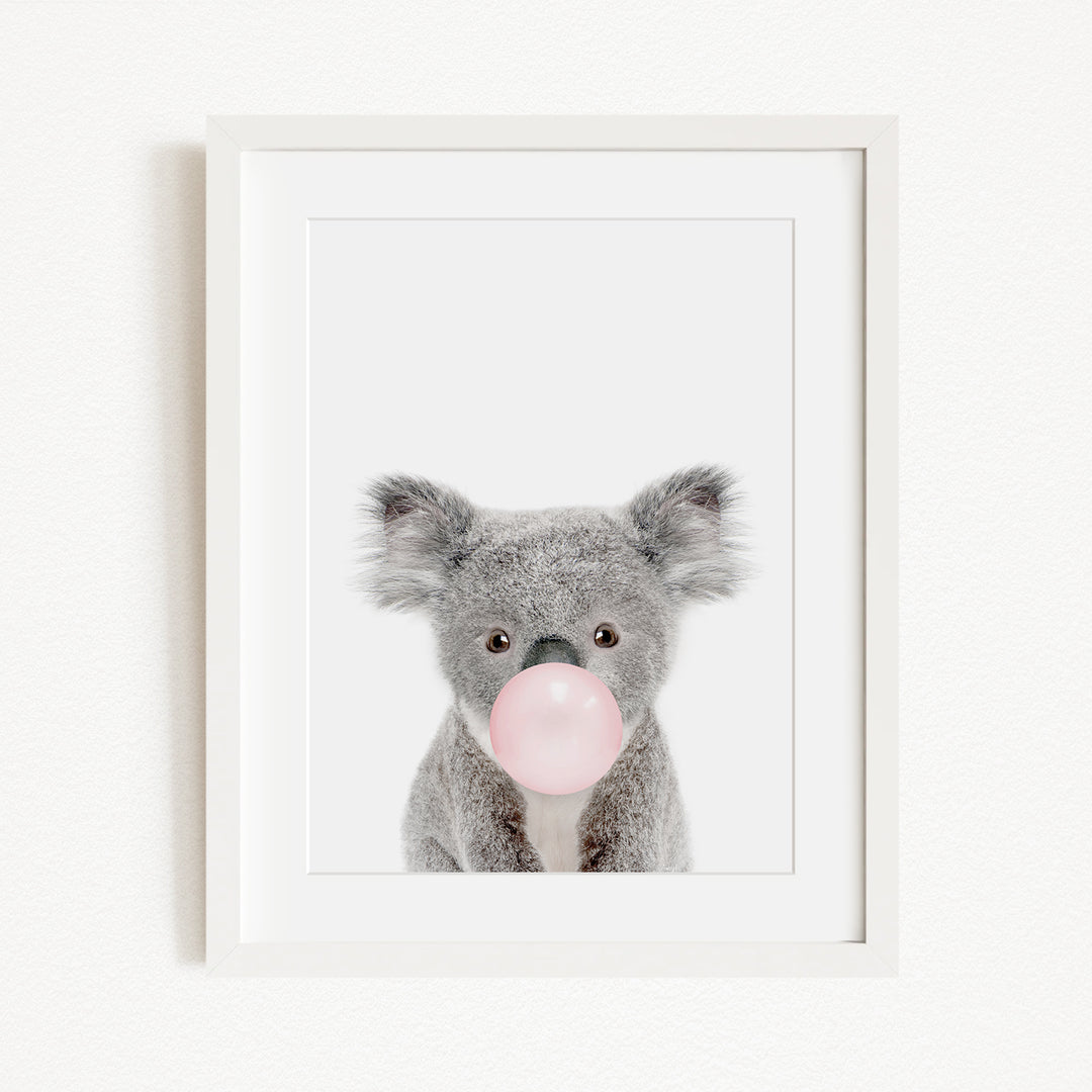 A cute koala bear blowing a bubble with a pink bubble gum bubble.