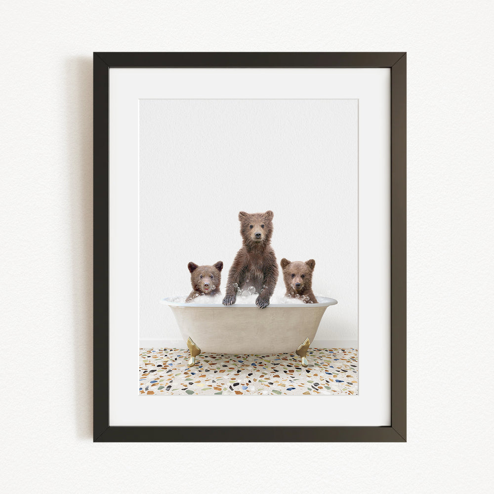 A framed image depicting three bears sitting in a bathtub, with one bear standing in the center and the other two sitting around it.
