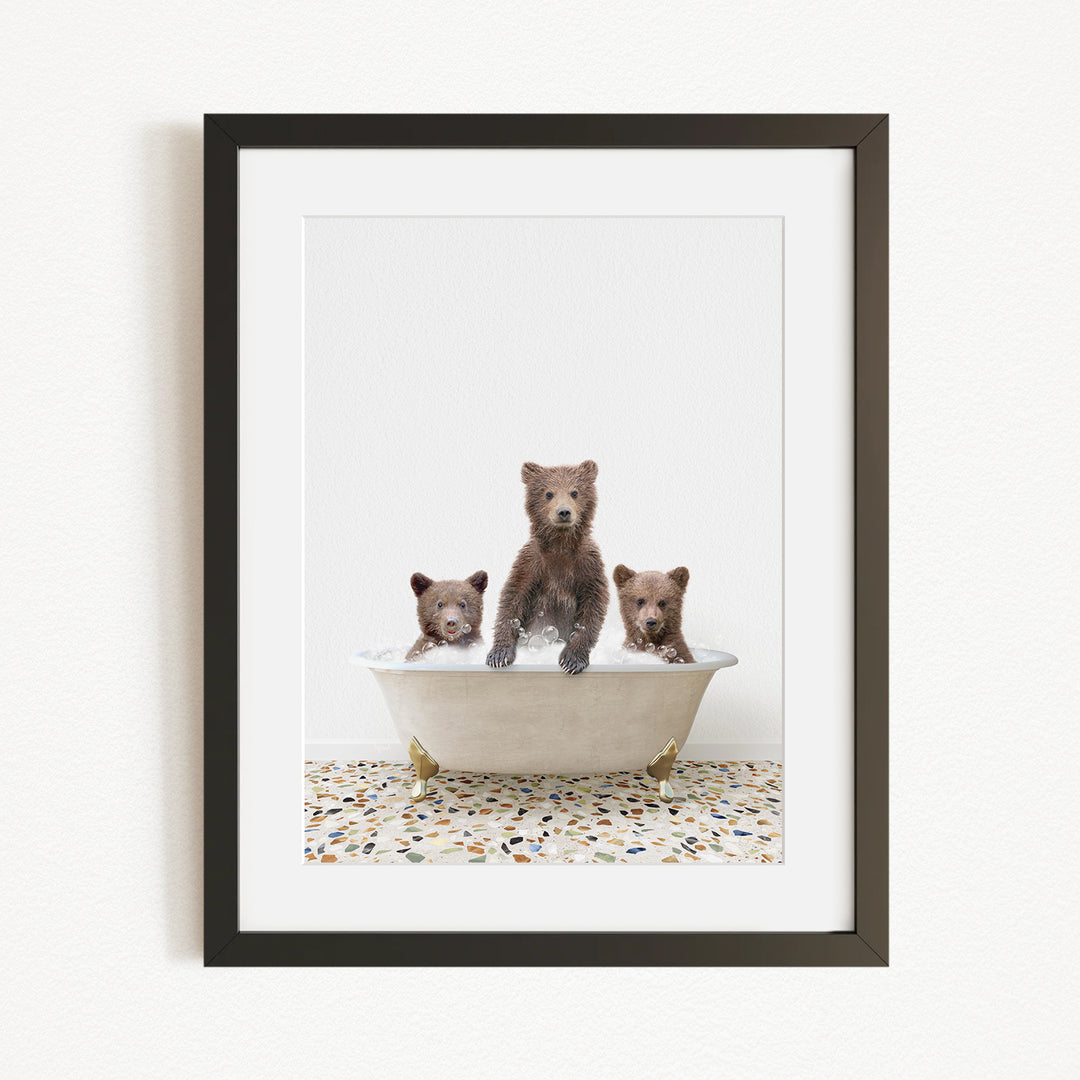 A framed image depicting three bears sitting in a bathtub, with one bear standing in the center and the other two sitting around it.