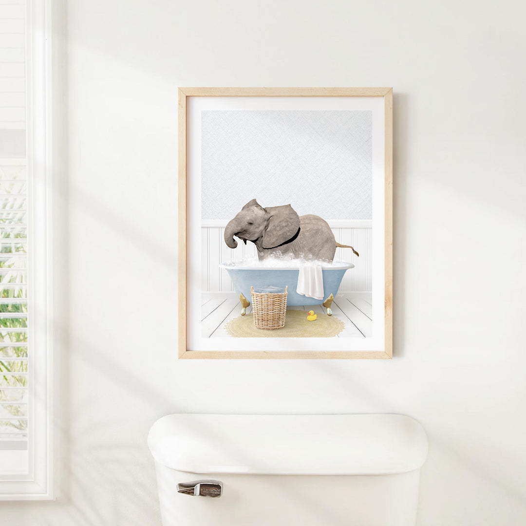 A framed image of an elephant sitting in a bathtub, surrounded by various objects such as a basket and a towel.