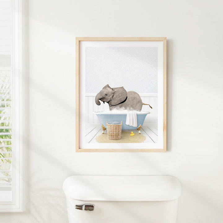 A framed image of an elephant sitting in a bathtub, surrounded by various objects such as a basket and a towel.