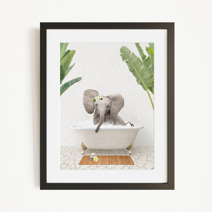 A gray elephant is sitting in a white bathtub, surrounded by green leaves, with a wooden mat on the floor in front of the tub.