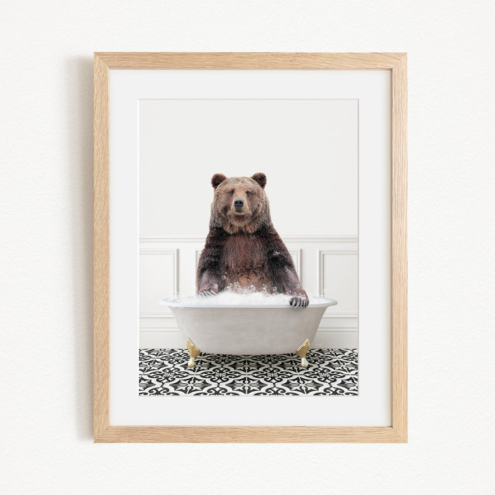 A brown bear sitting in a white bathtub filled with bubbles, with a black and white patterned floor beneath it.