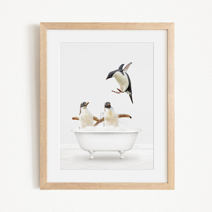 A framed image depicting two penguins sitting in a bathtub, with one penguin flying towards the other penguin.