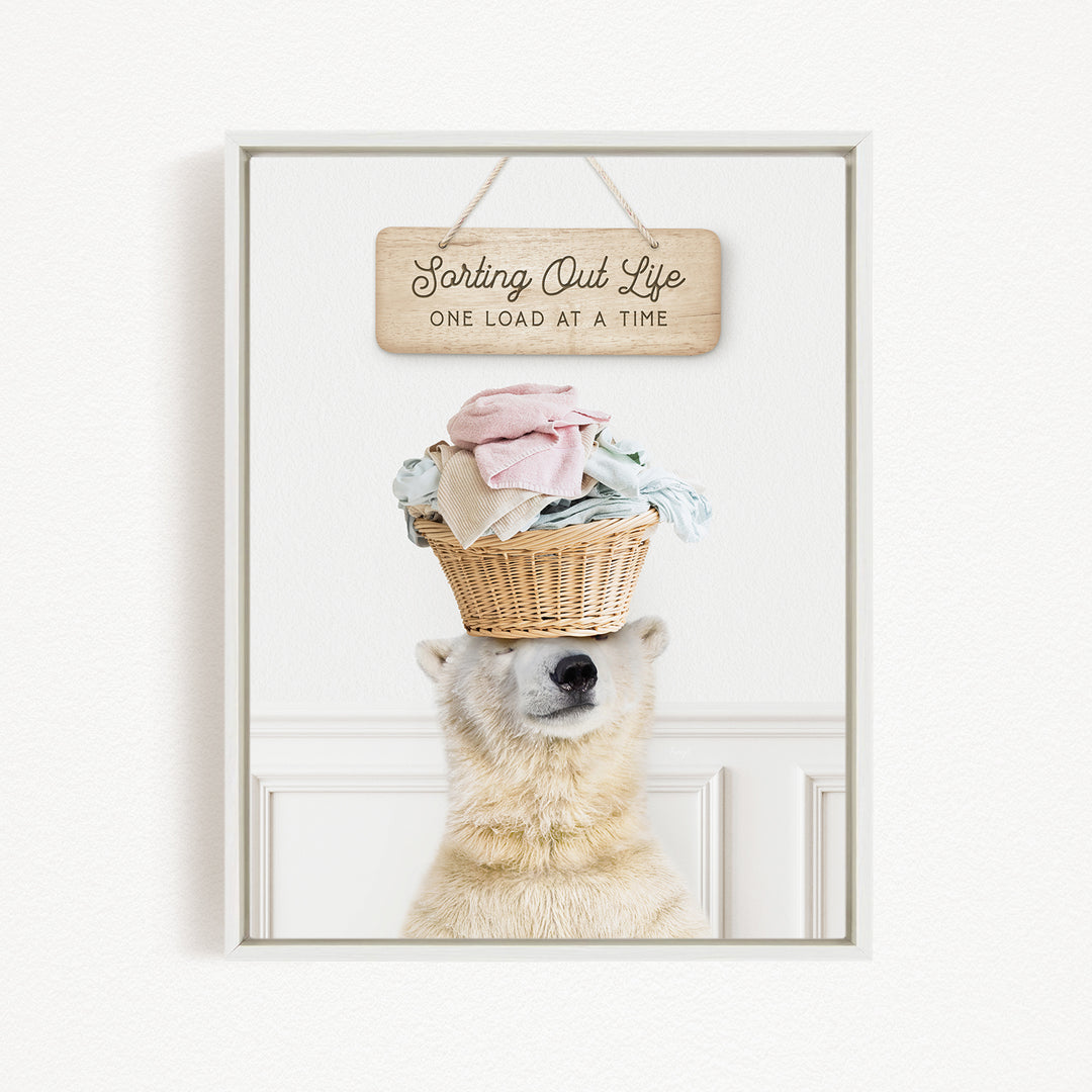 A polar bear balancing a basket of laundry on its head, with a wooden sign above that reads "Sorting Out Life One Load at a Time".