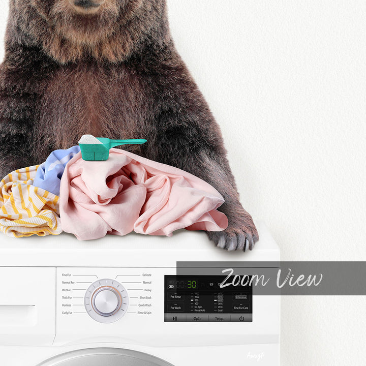 A bear sitting on top of a washing machine, surrounded by laundry.