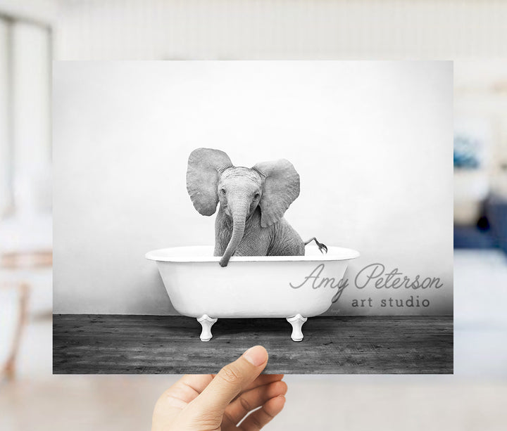 a hand holding up a black and white photo of an elephant in a bathtub