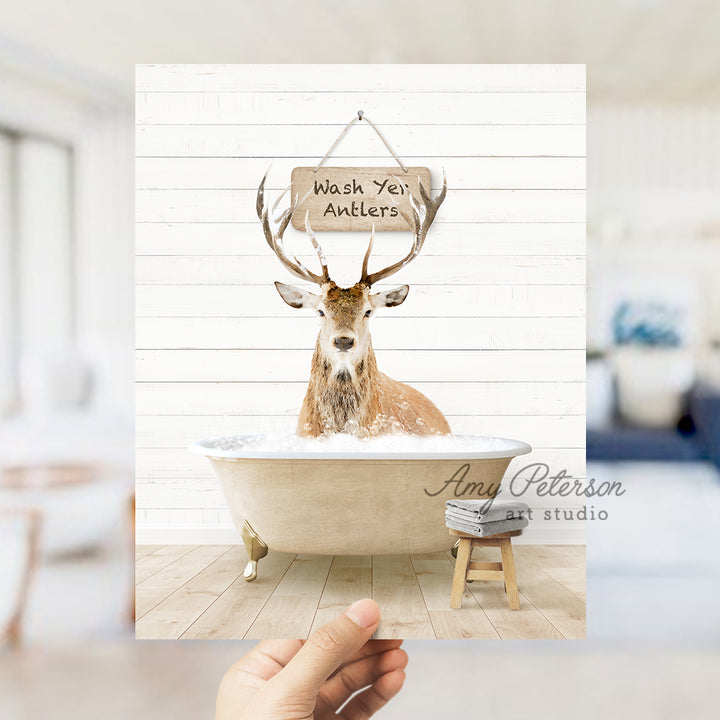 a hand holding up a photo of a deer in a bathtub