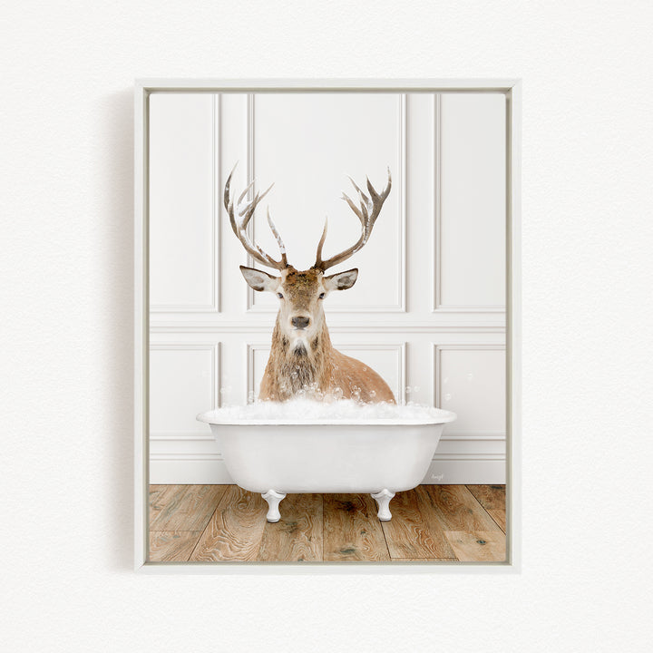 A deer with large antlers is sitting in a white bathtub filled with water, creating a whimsical and unexpected scene.