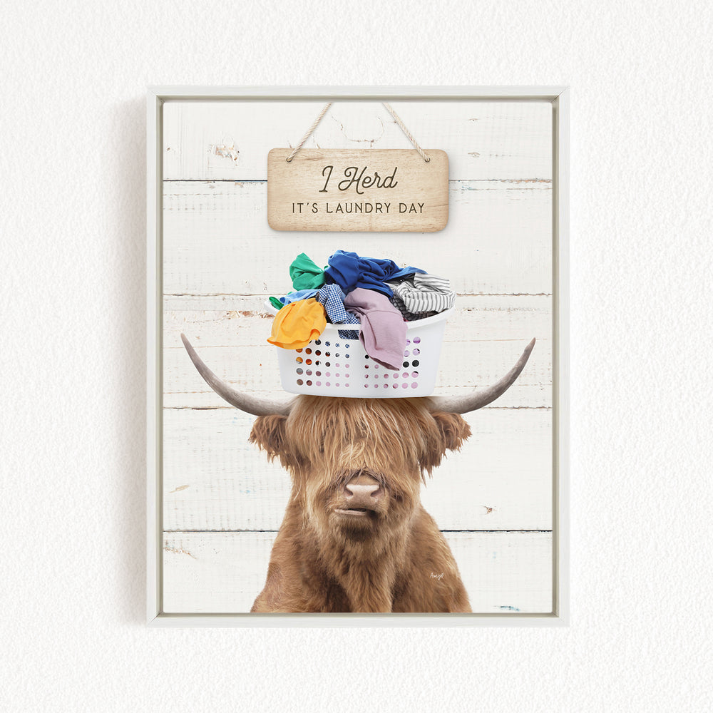 A humorous image of a Highland cow with a basket of laundry on its head, accompanied by a wooden sign that reads "It's laundry day".