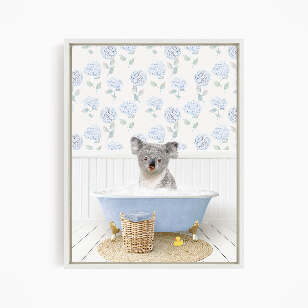 A koala bear sitting in a blue bathtub filled with water, surrounded by a wicker basket and a yellow rubber duck.
