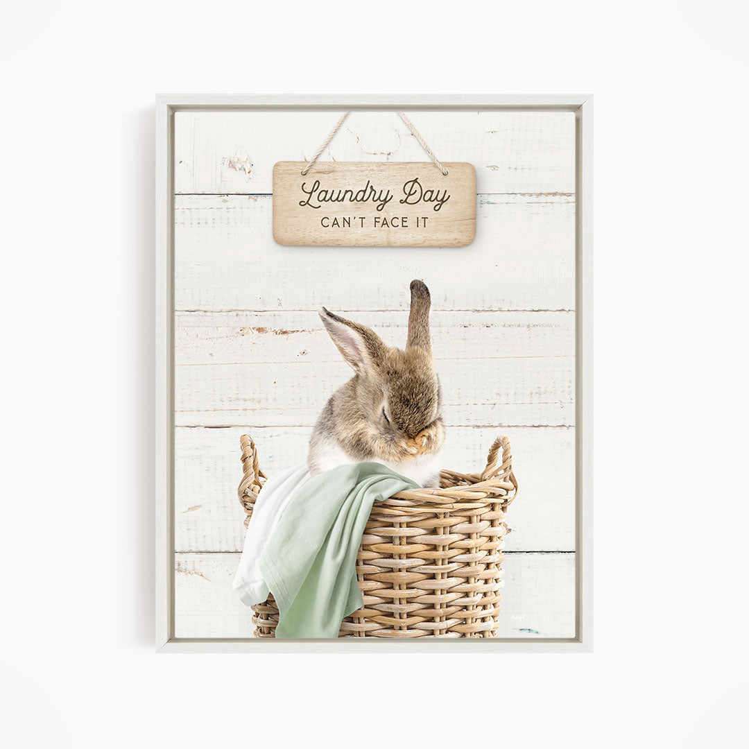 A cute rabbit sitting in a wicker basket, with a wooden sign above that says "Laundry Day Can't Face It".