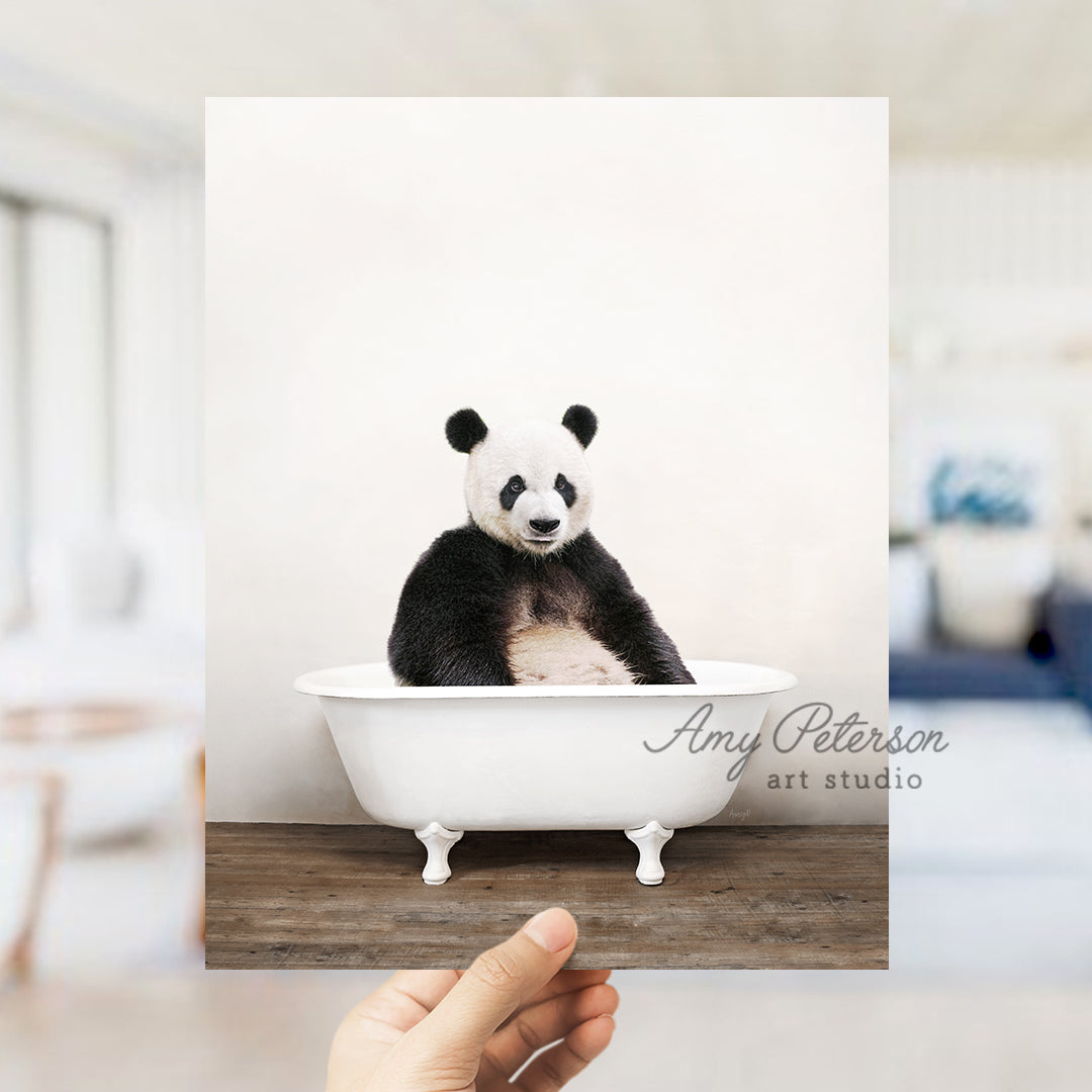 a hand holding a photo of a panda bear in a bathtub