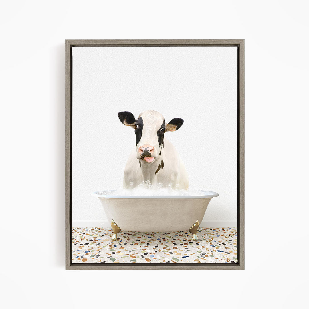 A black and white cow is sitting in a white bathtub filled with water, creating a whimsical and humorous scene.
