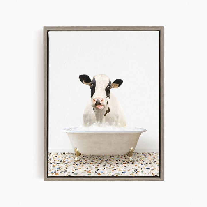 A black and white cow is sitting in a white bathtub filled with water, creating a whimsical and humorous scene.