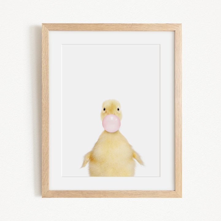 A cute yellow duck blowing a bubble with a pink bubble gum bubble.