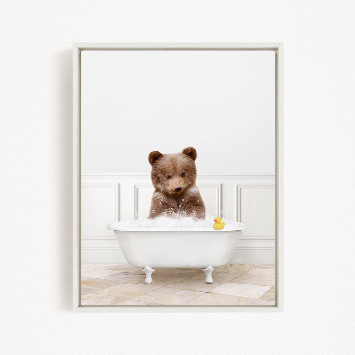 A brown bear sitting in a white bathtub, with a rubber duck floating in the water.