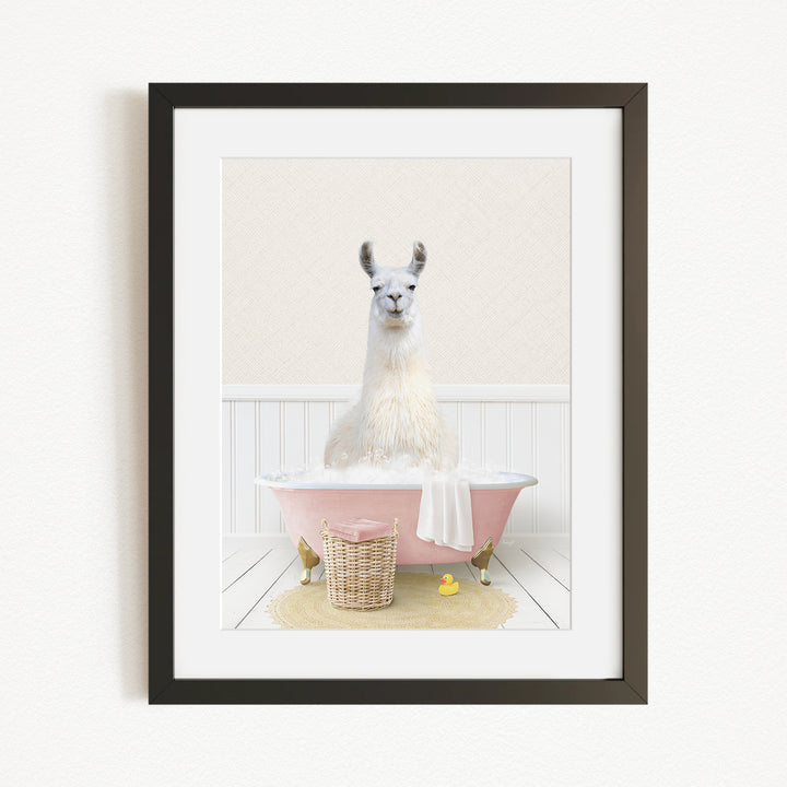 A white llama sitting in a pink bathtub, surrounded by a yellow rubber duck and a wicker basket.