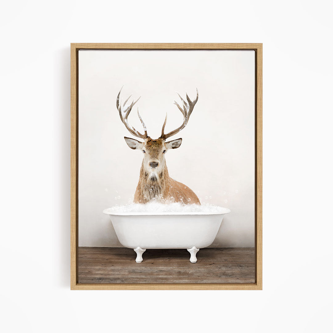 A deer with large antlers is sitting in a white bathtub filled with bubbles, creating a whimsical and unexpected scene.